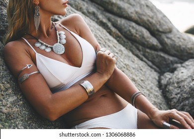 Foto do modelo bonito estilo boho vestindo maiô branco e prata boêmio jóias na praia no pôr do sol