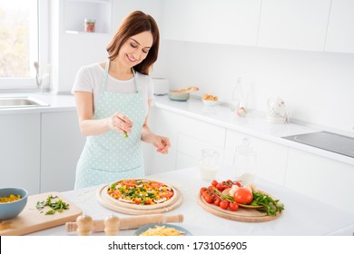 Photo Of Beautiful Cheerful Housewife Enjoy Hobby Cooking Family Recipe Dinner Pizza Add Final Last Ingredient Before Putting In Oven Wear T-shirt Apron Standing Modern Kitchen Indoors