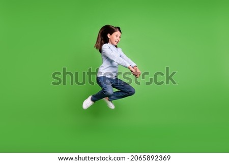 Photo of beautiful funky schoolgirl wear blue turtleneck jumping high riding horse smiling isolated green color background