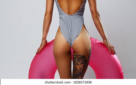 Photo of a beautiful girl in a swimsuit with a sports figure and hipster tattoos on a white background.