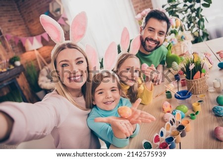 Photo of beautiful idyllic family four people take selfie showing painted eggs wear bunny ears home indoors