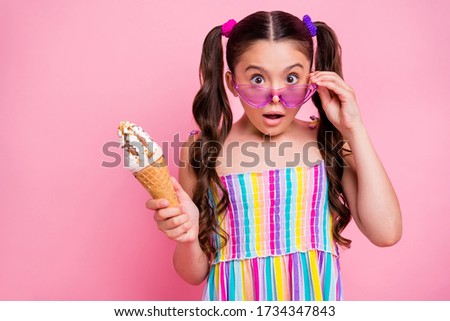Photo of beautiful little lady taking off sun specs open mouth two cute curly long tails hold big cone ice cream delicious wear colored summer dress isolated pastel pink color background