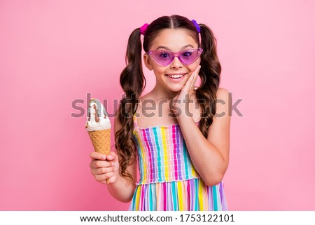 Photo of beautiful little lady two cute curly long tails hold big cone ice cream gelato hand on cheek delicious wear cool sun specs colored summer dress isolated pastel pink color background