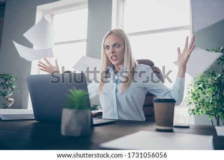 Photo of beautiful outraged business lady look notebook table arms throwing papers documents air project epic fail lose big money wear shirt sitting chair modern interior office indoors