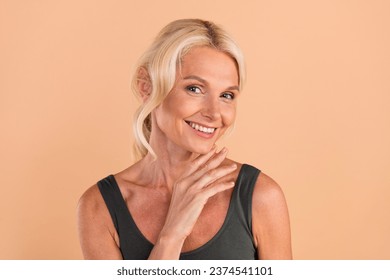 Photo of beautiful toothy smile nice senior woman touching neck posing skincare wellbeing cream applying isolated on beige color background: stockfoto