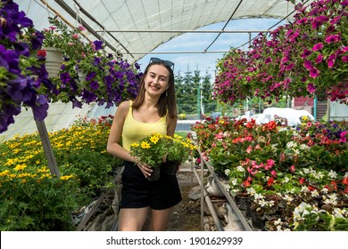 Photo of beautiful young girl posing between flowers in a greenhouse. Lifestyle