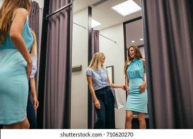 Photo of a beautiful young woman asking for a friend's opinion in the fitting room.