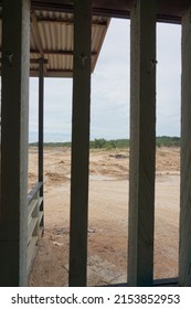 Is A Photo Behind A Wooden Window Showing A Barren Land Without Crops Due To Mining Exploitation