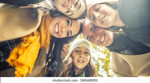 Photo From Below On A Happy Family With Three Kids Smiling, Putting Their Heads Together.