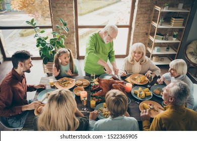 Photo of big family sit feast meals table around blessing roasted turkey eldest grandfather making slices hungry relatives waiting excited in living room indoors