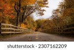 Photo of bike path during fall with colored leaves and wooden fence in Burlington, Vermont