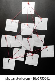 Photo of a black detecftive board with blank paper linked by red thread. - Shutterstock ID 1863953662