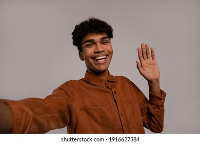 Photo Of Black Man Takes A Selfie And Smiles With Perfect Teeth. Male Wears Shirt, Isolated Grey Color Background