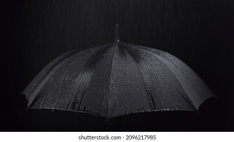 Photo of the black umbrella and rainy drops on black background