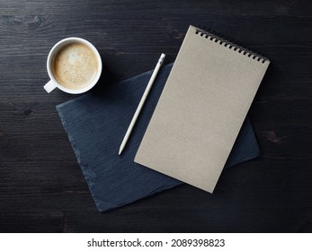 Photo of blank kraft notepad, pencil and coffee cup. Branding mock up. Top view. Flat lay.