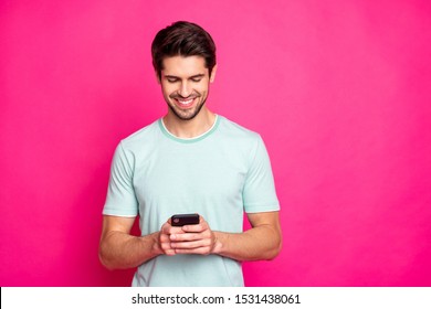 Photo of blogger guy holding telephone in hands checking subscribers toothy smiling wear casual outfit isolated vivid pink color background