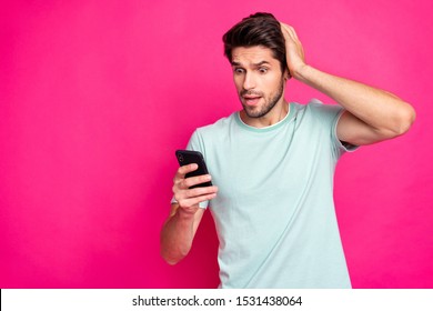 Photo of blogger guy holding telephone in hands checking subscribers noticed many unfollowers wear casual outfit isolated vivid pink color background