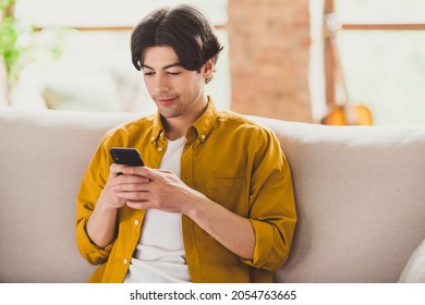Photo of blogger influencer positive nice man hold telephone blogging sit comfy sofa wear yellow shirt home indoors