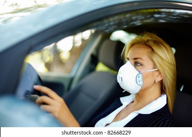 Photo of blond female wearing respirator while driving car in polluted area