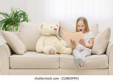 Photo Of Blond Girl Reading A Book To Her Toy Plush Friend.