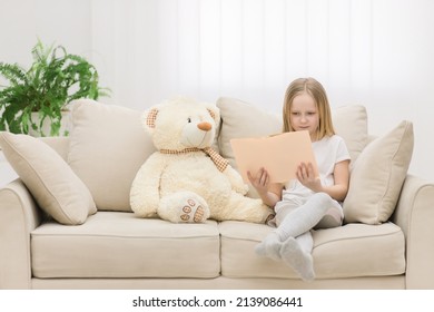 Photo Of Blond Girl Reading A Book To Her Toy Plush Friend.