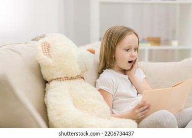 Photo Of Blond Girl Reading A Book To Her Toy Plush Friend.