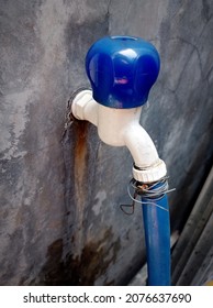 Photo of a blue faucet with a plastic pipe connected to it tied with a piece of wire, very unique