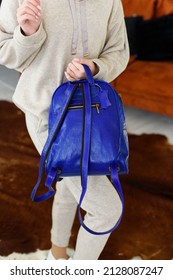 Photo Of A Blue Leather Backpack In Womens Hand. Girl Wearing Beige Sports Suit. Selective Focus