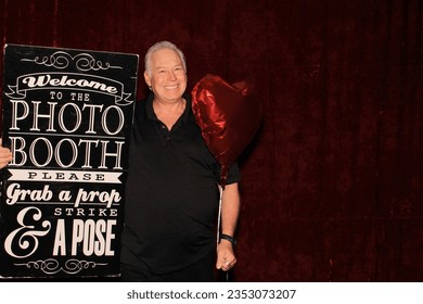 Photo Booth. A man Smiles and Laughs as he poses for his picture to be taken while in a Photo Booth at a Party. Photo Booths are loved at Weddings and all Parties. Guest pose for photos. Photo Booth.  - Powered by Shutterstock