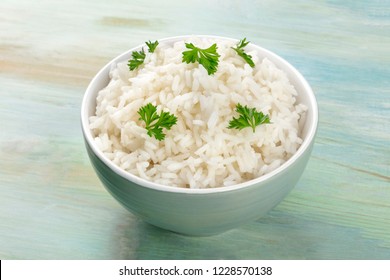A photo of a bowl of cooked white long rice on a teal blue background with a place for text
