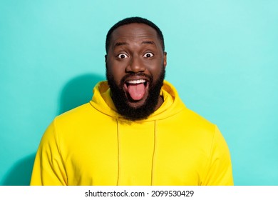 Photo of brunette funky millennial beard guy tongue out wear yellow sports cloth isolated on turquoise color background
