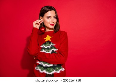 Photo of brunette hair lady hold ornament ball want new earrings on eve wear theme party sweater isolated over red color background