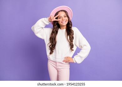 Photo of brunette long hairdo sweet girl show v-sign wear cap sweater trousers isolated on violet color background