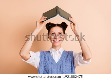 Photo of brunette optimistic lady read book hands up wear spectacles white shirt blue vest isolated on beige color background