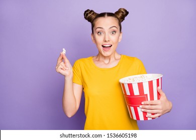 Photo of brunette white trendy cheerful millennial watching movie excited about unexpected events in plot holidng bucket of pop corn expressing amazed emotions isolated violet pastel color background