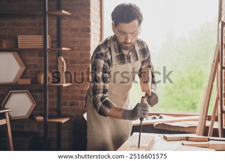 Photo of builder guy woodworker using tools hammer chisel for production garage indoors