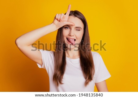 Photo of bully lady show tongue finger forehead mocking wear white t-shirt posing on yellow background