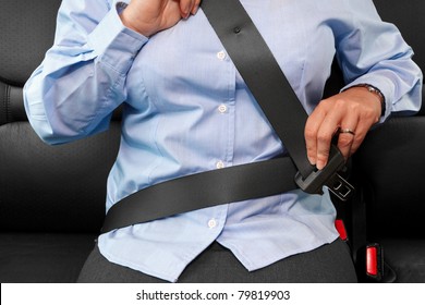 Photo of a business woman sitting in a car putting on her seat belt