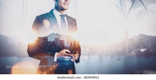 Photo of businessman holding smart phone. Double exposure photo of panoramic city view at sunrise  - Powered by Shutterstock