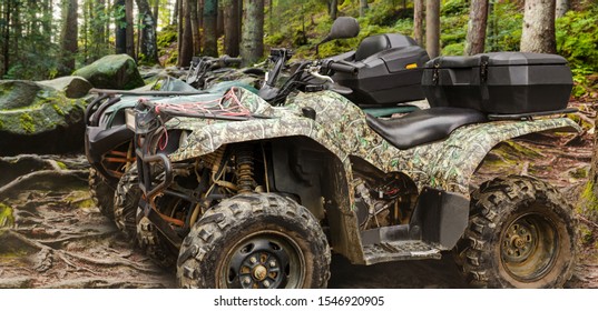Photo of a camouflaged hunting offroad atv vehicles standing in forest profile  view.