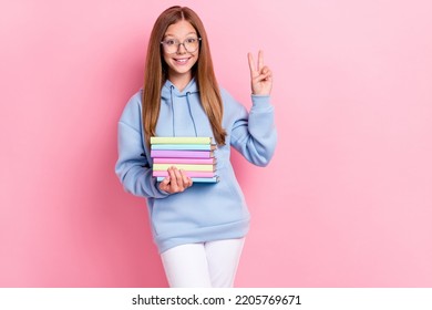 Photo of candid friendly smart girl hold book hand fingers demonstrate v-sign isolated on pink color background