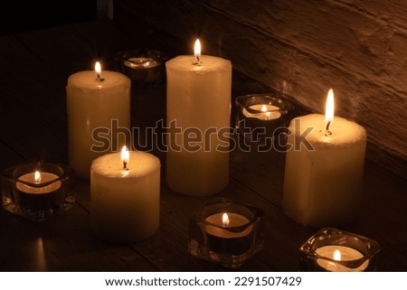 photo of candles of different sizes burning near the wall
