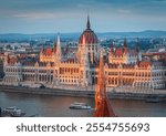 The photo captures the Hungarian Parliament Building in Budapest during sunset, beautifully reflecting the warm sunlight on its Neo-Gothic architecture along the Danube River.