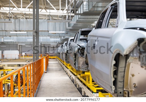 Photo of car bodies on assembly line. Factory\
for production of autos. Modern automotive industry. Electric car\
factory, conveyor
