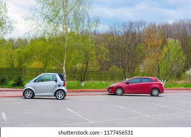 Photo Of Car Parking With Small White And Red Cars Near The Park