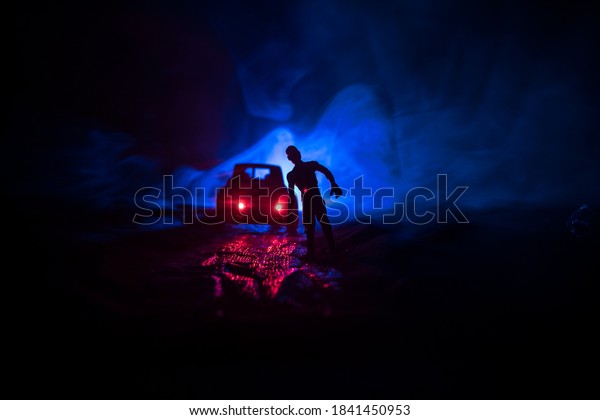 photo of a car stopped on the road lighting up a
zombies. Silhouette terrible zombie night near the car. Miniature
decoration. Selective
focus