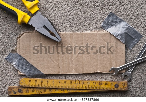 Photo of an cardboard piece taped with duct tape\
rounded by mechanic tools