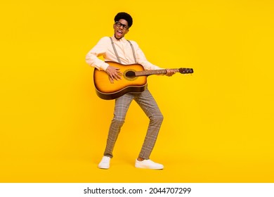 Photo of carefree entertainer guy hold guitar play composition wear suspenders shirt isolated yellow color background - Powered by Shutterstock