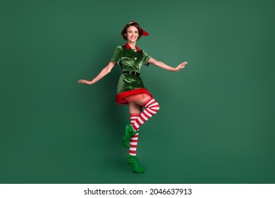 Photo of carefree funky lady dance stand tiptoe wear elf costume hat high socks isolated green color background