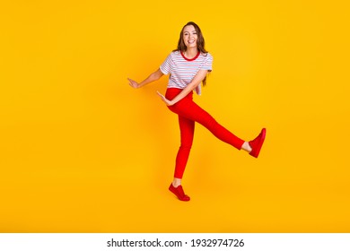 Photo of carefree lady dance have fun wear striped shirt red trousers sneakers isolated yellow color background - Shutterstock ID 1932974726